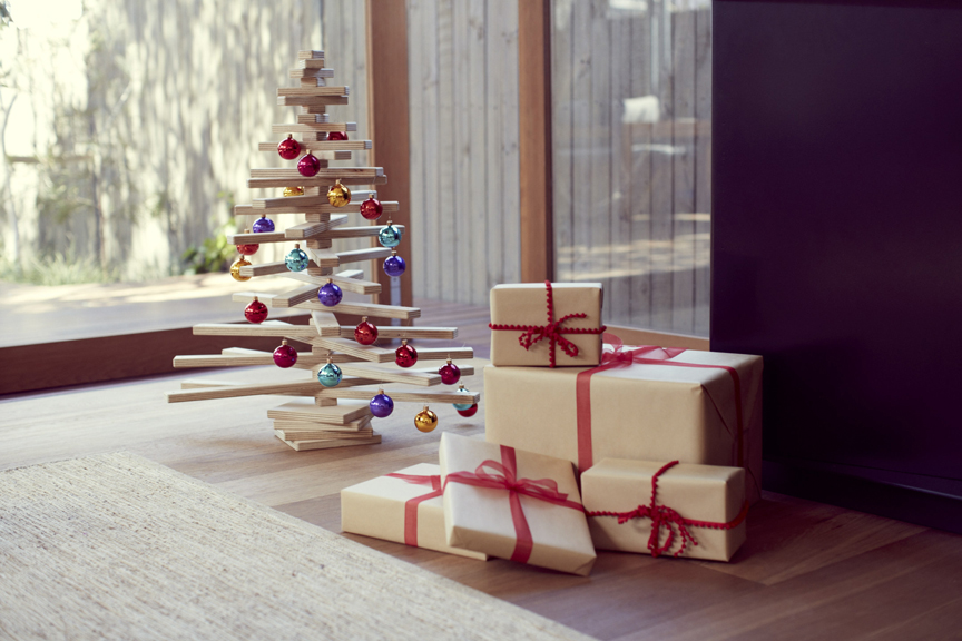 Wooden Christmas Tree Decorated with Colorful Baubles and Christmas Presents next to it.