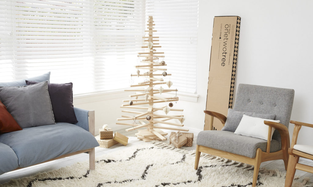 One Two Tree Christmas Tree decorated in a room with its packaging next to it.